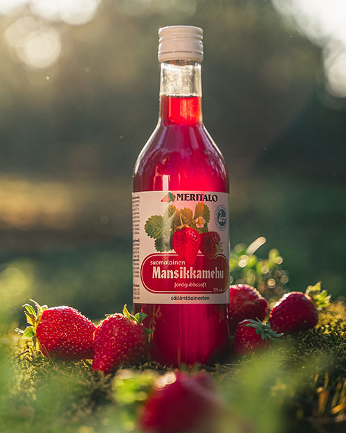Meritalo strawberry juice 375 ml in nature in sunlight surrounded by strawberries